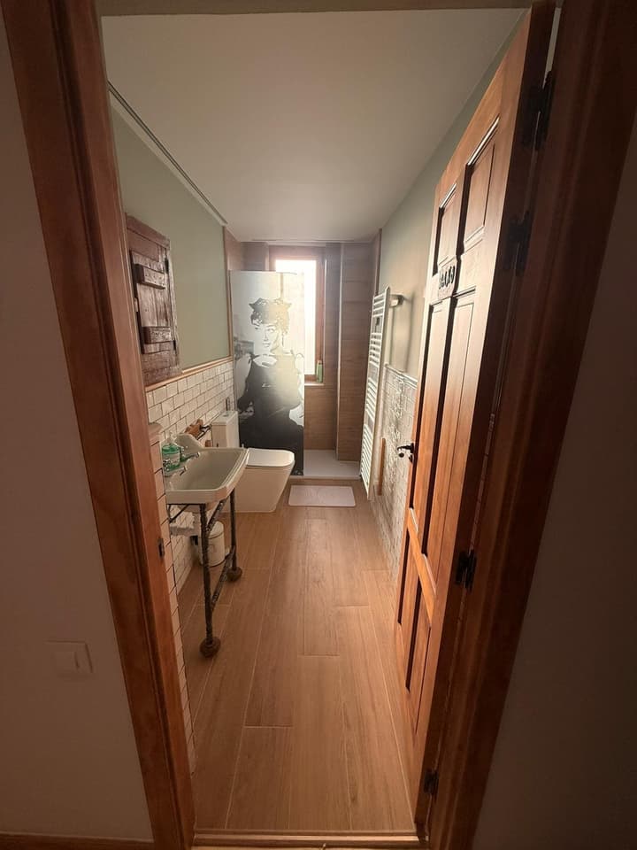 Baño reformado con azulejo tipo metro blanco, lavabo de estilo vintage y mampara decorada