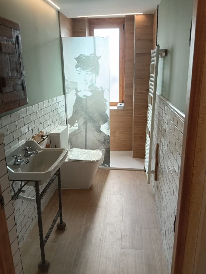 Baño reformado con ducha de obra, azulejo tipo metro blanco y toallero radiador