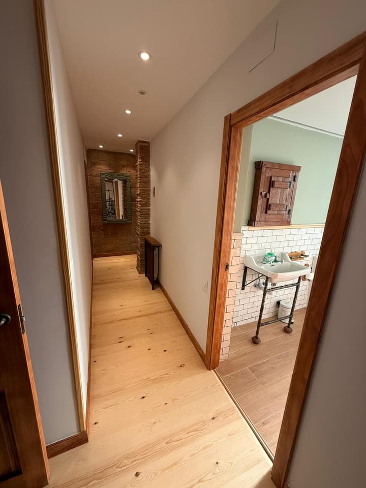 Distribuidor reformado con tarima de pino y vista al baño con lavabo vintage