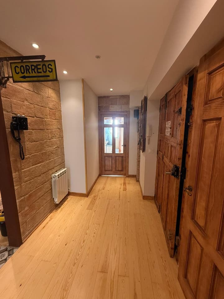 Recibidor reformado con pared de ladrillo caravista, tarima de pino y puertas antiguas restauradas
